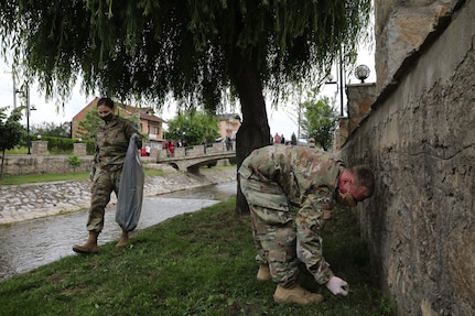 Spc. Jamie Harrison and Sgt. Aaron Crane of Kosovo Force Regional Command East Liaison Monitoring Team “Kilo 20” pick up trash along a creek of Vitina/Viti, Kosovo, June 5, 2020. LMT personnel from “Kilo 20” out of Camp Bondsteel and Maneuver Battalion personnel out of Camp Nothing Hill participated in area beautification in observation of World Environment Day.