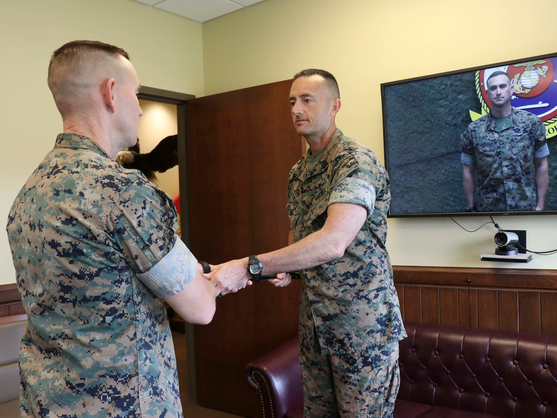 U.S. Marine Corps Sgt.Maj. Christopher Adams (center), the outgoing Sergeant Major of U.S. Marine Corps Security Force Regiment (MCSFR), Fleet Marine Force Atlantic, U.S. Marine Corps Forces Command, hands a noncommissioned officer sword to Col. Corey M. Collier (left), the commanding officer of MCSFR, during a relief and appointment ceremony June 3, 2020 at Naval Weapons Station Yorktown, Virginia. The ceremony was conducted virtually, as part of MCSFR’s COVID-19 response measures, and signifies the passing of responsibilities from Sgt.Maj. Christopher Adams to Sgt.Maj. Christopher J. Easter as the Regimental Sergeant Major for MCSFR. (U.S. Marine Corps photo by Staff Sgt. Jessika Braden/ Released)