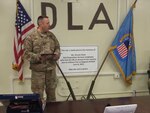 Army Lt. Col. Ryan Mendenhall, officer-in-charge for DLA Disposition Services in Afghanistan, addresses his team as they assemble by the memorial display to remember fallen employee Krissie Davis and her sacrifice.