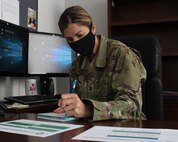 Lt. Col. Gail Smicklas, 50th Space Wing inspector general, takes notes in her office June 5, 2020, at Schriever Air Force Base, Colorado. Since COVID-19 falls under public health emergency and disaster preparedness, the 50th SW IG decided to use the pandemic to test the base’s readiness. (U.S. Air Force photo by Marcus Hill.)