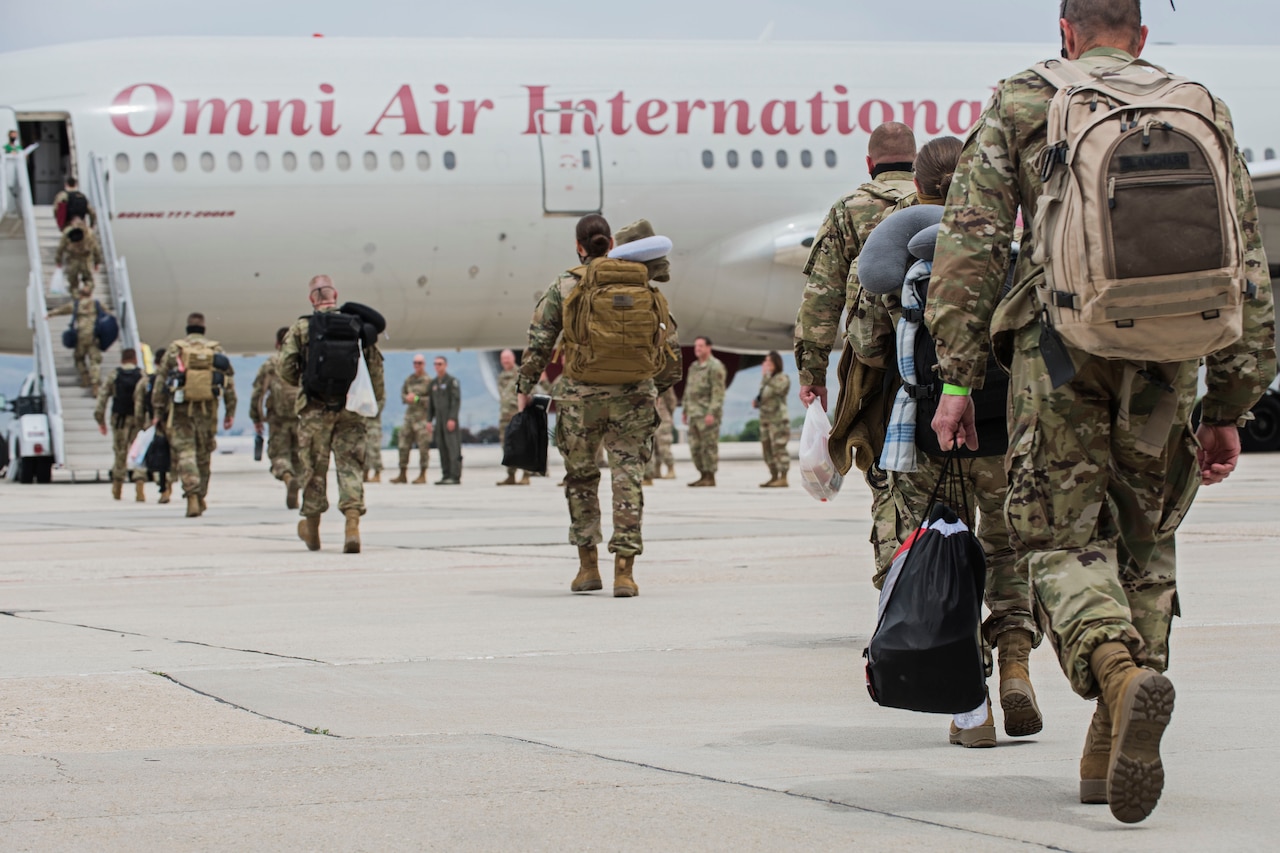 Airmen board a commercial-contract airliner for a deployment.