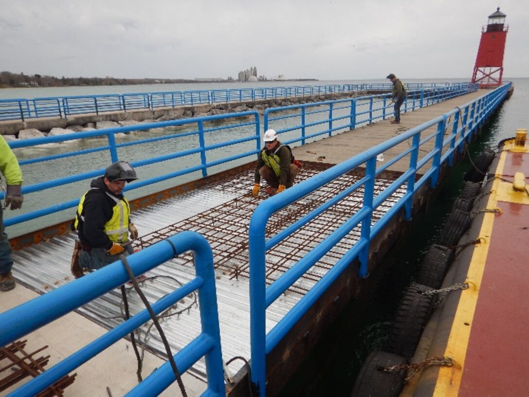 The Detroit District floating plant out of Kewaunee, Wisconsin completed repairs to the storm-damaged concrete panels of the Charlevoix South Pier in Charlevoix, Michigan. The broken pre-cast panels were removed and replaced with an updated design with corrugated steel, rebar and cast in place concrete.