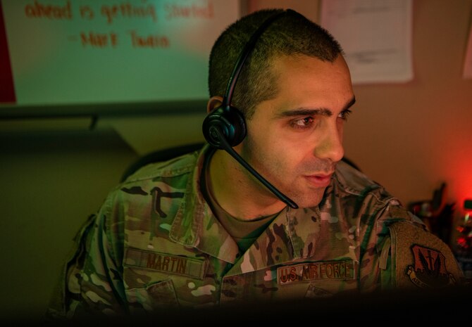 An Airman answers a phone call using a head set.