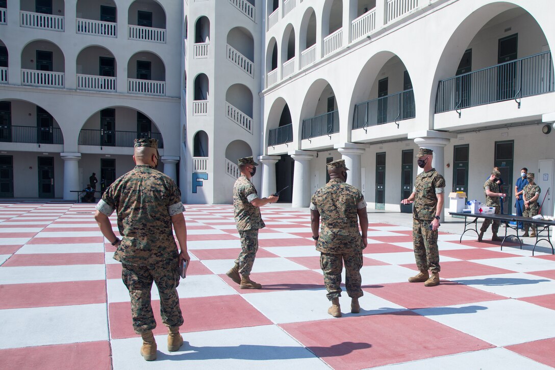 Marines wearing masks stand in a dormitory courtyard.
