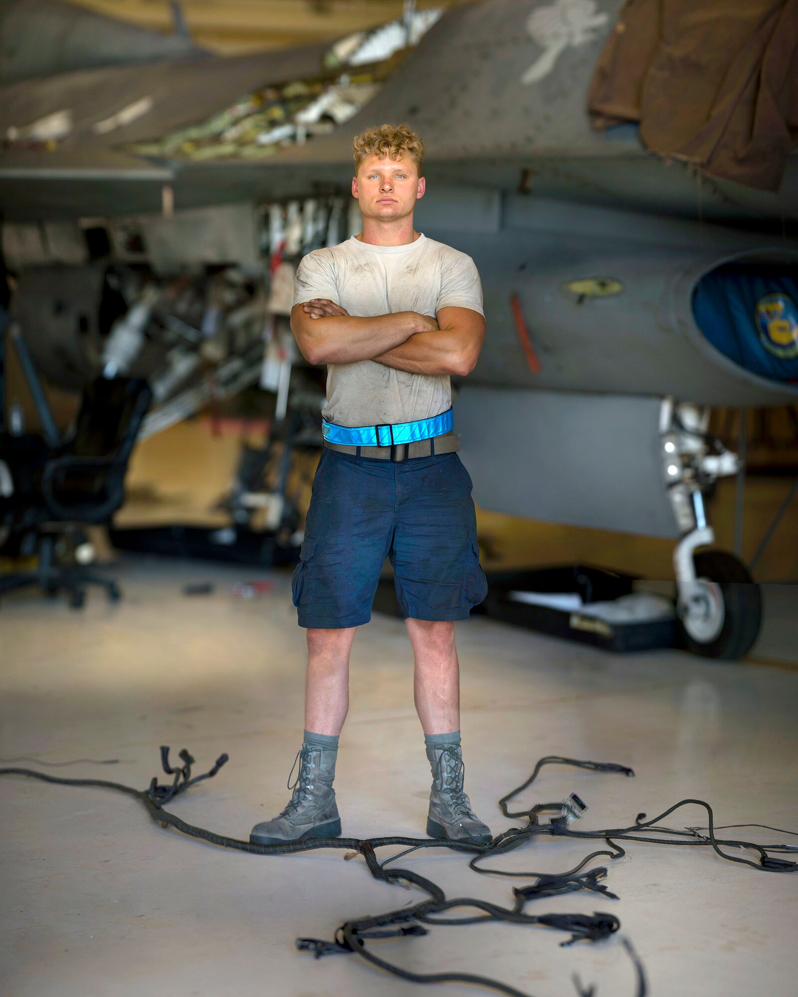 Senior Airman Brian Raatz, 311th Aircraft Maintenance Unit F-16 Viper crew chief poses for a photo, June 4, 2020, on Holloman Air Force Base, N.M. Three Airmen from the 311th AMU are replacing 11 wire harnesses throughout the plane that range up to 90 feet of wiring, which can take up to three months to repair. (U.S. Air Force photo illustration by Staff Sgt. Christine Groening)