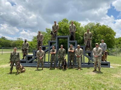 Military working dog handler training students from the Army, Air Force, Marine Corps and Navy pose for a photo following a K-9 demonstration for the Fair Oaks, Texas, Rotary Club June 3, 2020, at Joint Base San Antonio-Lackland.