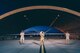 Three Airmen from the 432nd Aircraft Maintenance Squadron stand in front of an MQ-9 Reaper at night.