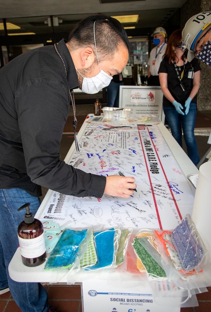 An employee from Puget Sound Naval Shipyard & Intermediate Maintenance Facility signs a C.A.R.E. pledge during an event held June 8 at the shipyard. Thousands of employees signed C.A.R.E. pledges and C.A.R.E. banners during the event, held at eight locations throughout the shipyard, staffed by shipyard leadership and volunteers from the Diversity Leadership Council, Employee Resource Groups, the Command Anti-Harassment and Discrimination and Employee Anti-Harassment and Discrimination Teams. Everyone who signed the pledge received a C.A.R.E. sticker, which they are authorized and encouraged to display on their hardhats.