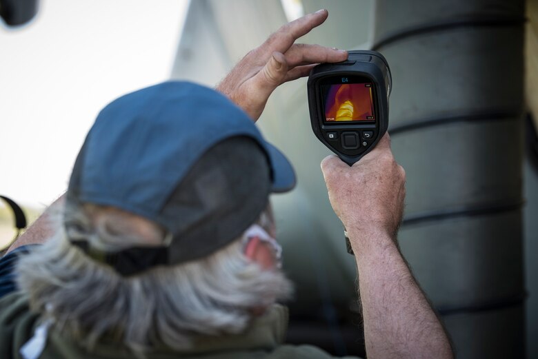 Bill Davis of Materials Engineering and Technical Support Services measures the temperature of ductwork during an Air Force Research Laboratory test to investigate the use of ground heaters to raise interior temperatures on C-17 aircraft. This test is part of an overall effort to demonstrate the effectiveness of using common equipment to heat aircraft to COVID-19 disinfection temperatures quickly and easily at virtually any military installation. (U.S. Air Force photo/Richard Eldridge)