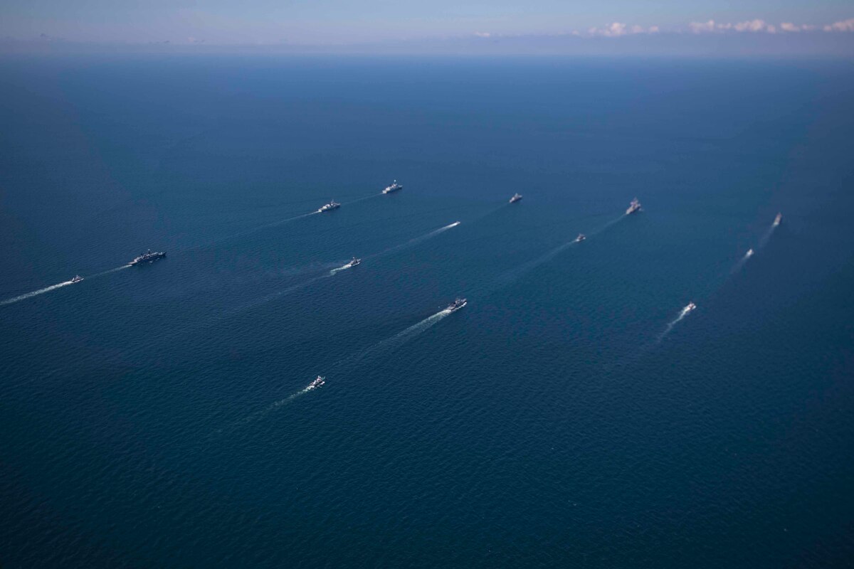 Ships of many nations steam in formation.