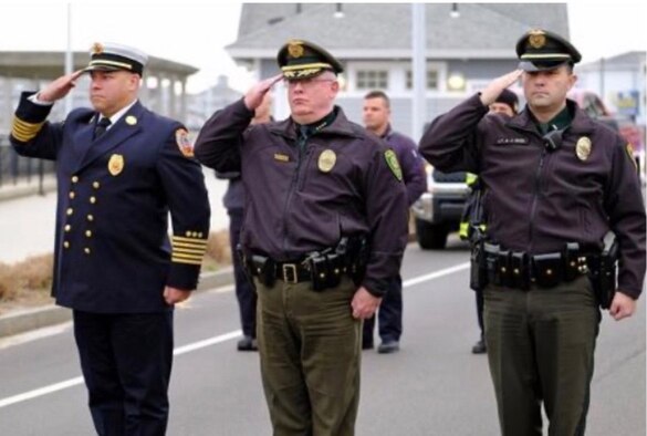 Chief Master Sgt. Alex Reno (left), 439th Maintenance Group superintendent, renders a salute. Reno works as a police officer in Hampton, New Hampshire when he's not in military status. (Courtesy Photo)