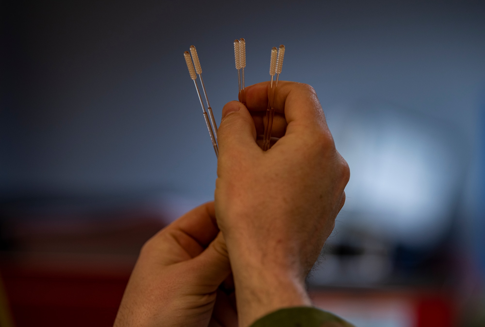 An Airman holds up six Nasopharyngeal swabs.