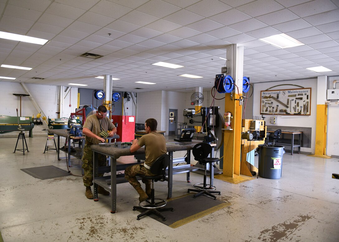 Tech. Sgts. Ryan McBride, 19th Maintenance Squadron NCO in charge of metals technology, and Jason Felts, 19th Maintenance Squadron sheet metal production lead, prepare a new 3D printed hydraulic pump bracket for installation at Little Rock Air Force Base, Arkansas, June 4, 2020. 3D printing the bracket will make it easier for C-130J maintenance units across the Air Force to obtain the part and eliminate the need to manufacture the part themselves. (U.S. Air Force photo by Airman 1st Class Jayden Ford)