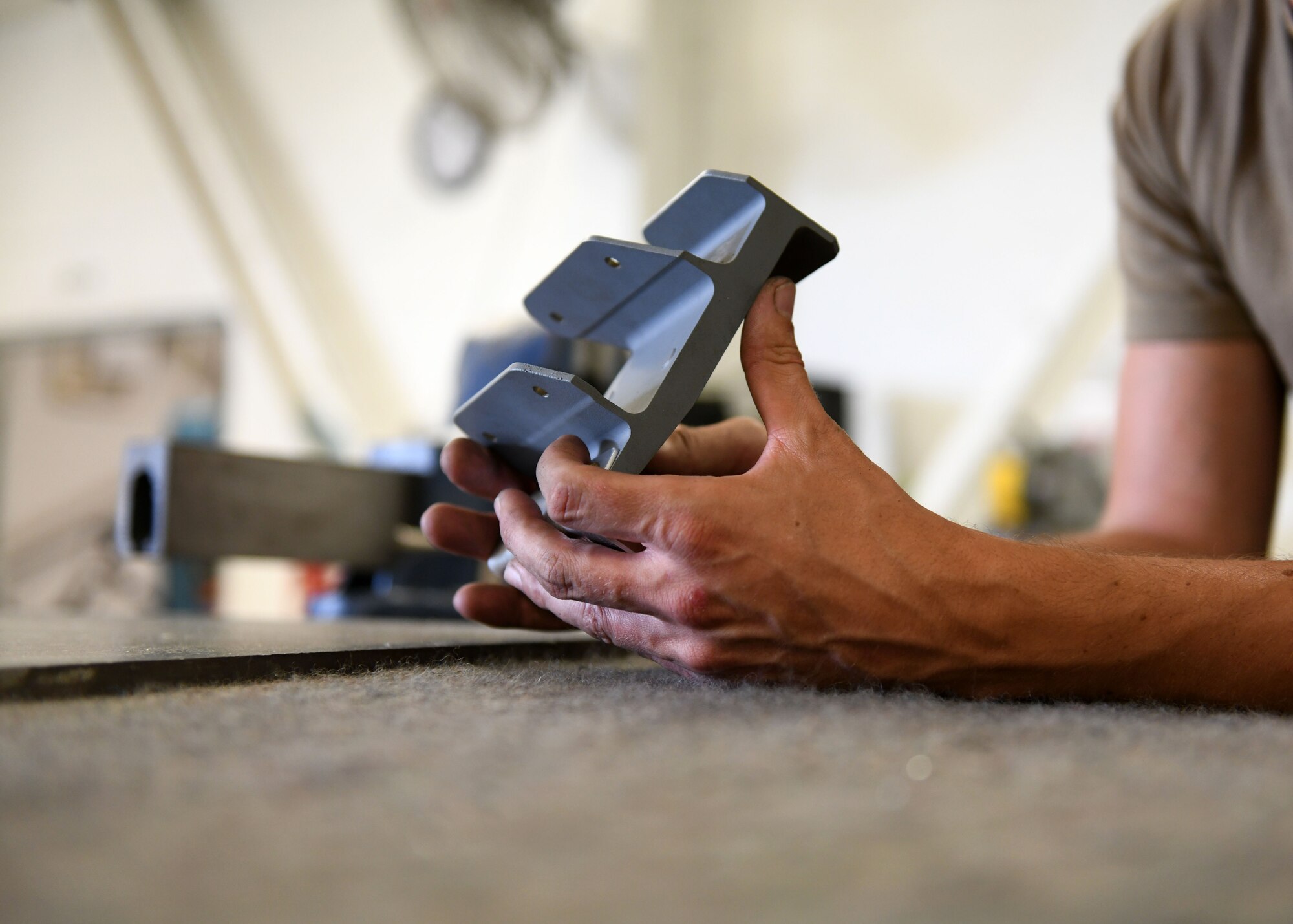 Tech. Sgt. Ryan McBride, 19th Maintenance Squadron NCO in charge of metals technology, inspects a new 3D printed hydraulic pump bracket at Little Rock Air Force Base, Arkansas, June 4, 2020. McBride pursued his idea of 3D printing the bracket by collaborating with Airmen from the Air Force Life Cycle Management Center. (U.S. Air Force photo by Airman 1st Class Jayden Ford)
