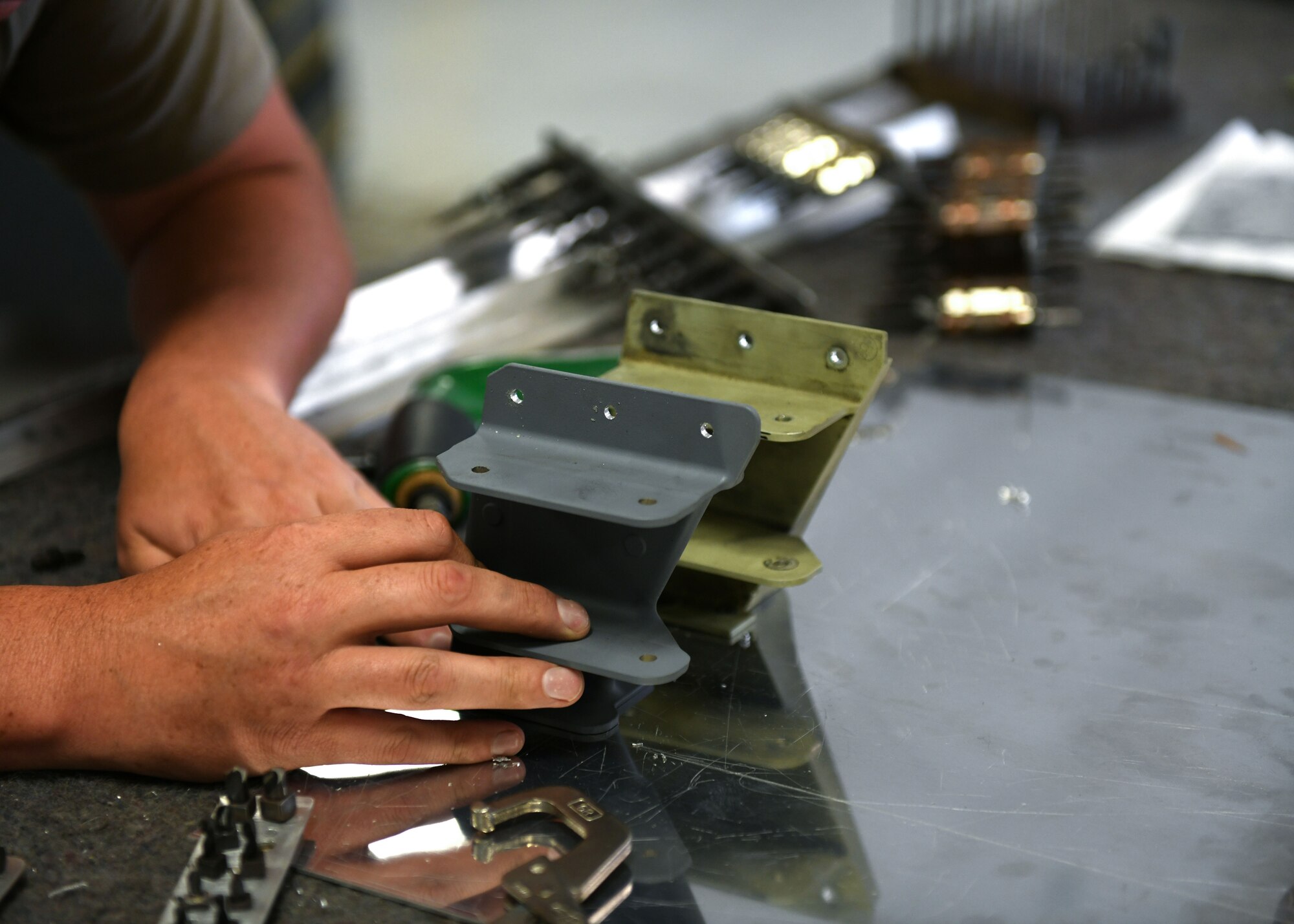Tech. Sgt. Jason Felts, 19th Maintenance Squadron sheet metal production lead, compares an old hydraulic pump bracket to the new 3D printed version at Little Rock Air Force Base, Arkansas, June 4, 2020. The re-creation of the part acted as an opportunity to completely revamp the structure and strength of the part to decrease the amount of repairs that are needed over time. (U.S. Air Force photo by Airman 1st Class Jayden Ford)