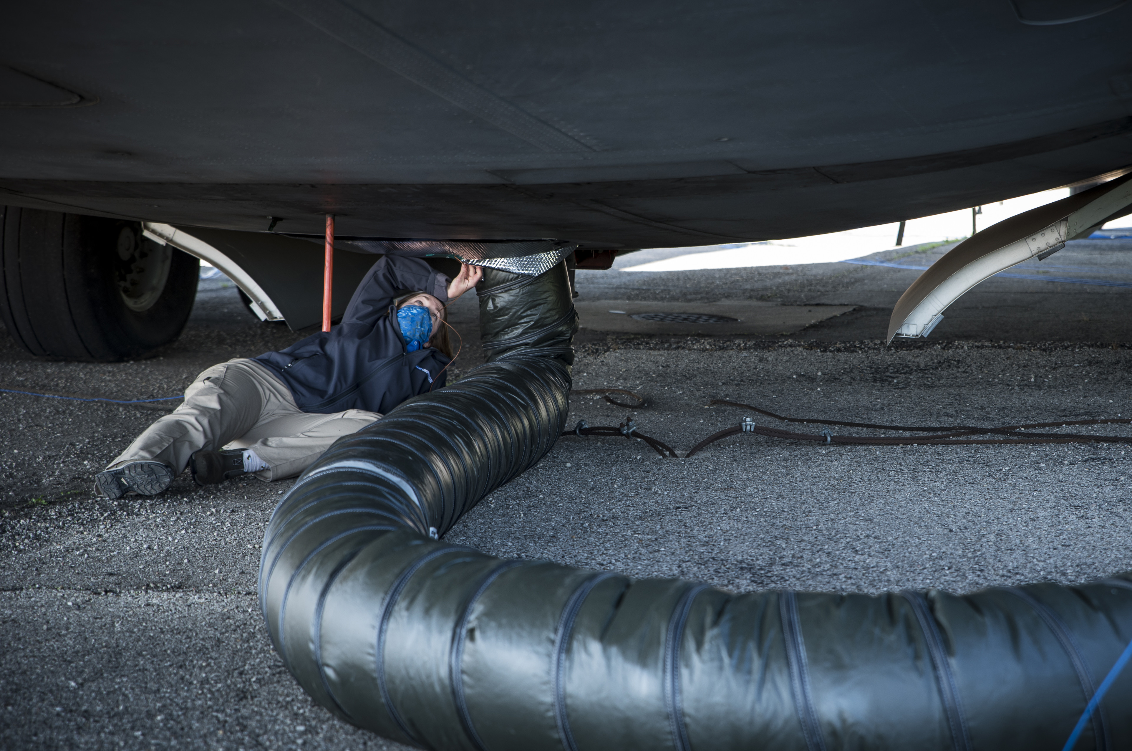 Dr. Angela Theys of Materials Engineering and Technical Support Services secures ductwork for an Air Force Research laboratory test to investigate the use of ground heaters to raise interior temperatures on C-17 aircraft. This test is part of an overall effort to demonstrate the effectiveness of using common equipment to heat aircraft to COVID-19 disinfection temperatures quickly and easily at virtually any military installation. (U.S. Air Force photo/Richard Eldridge)