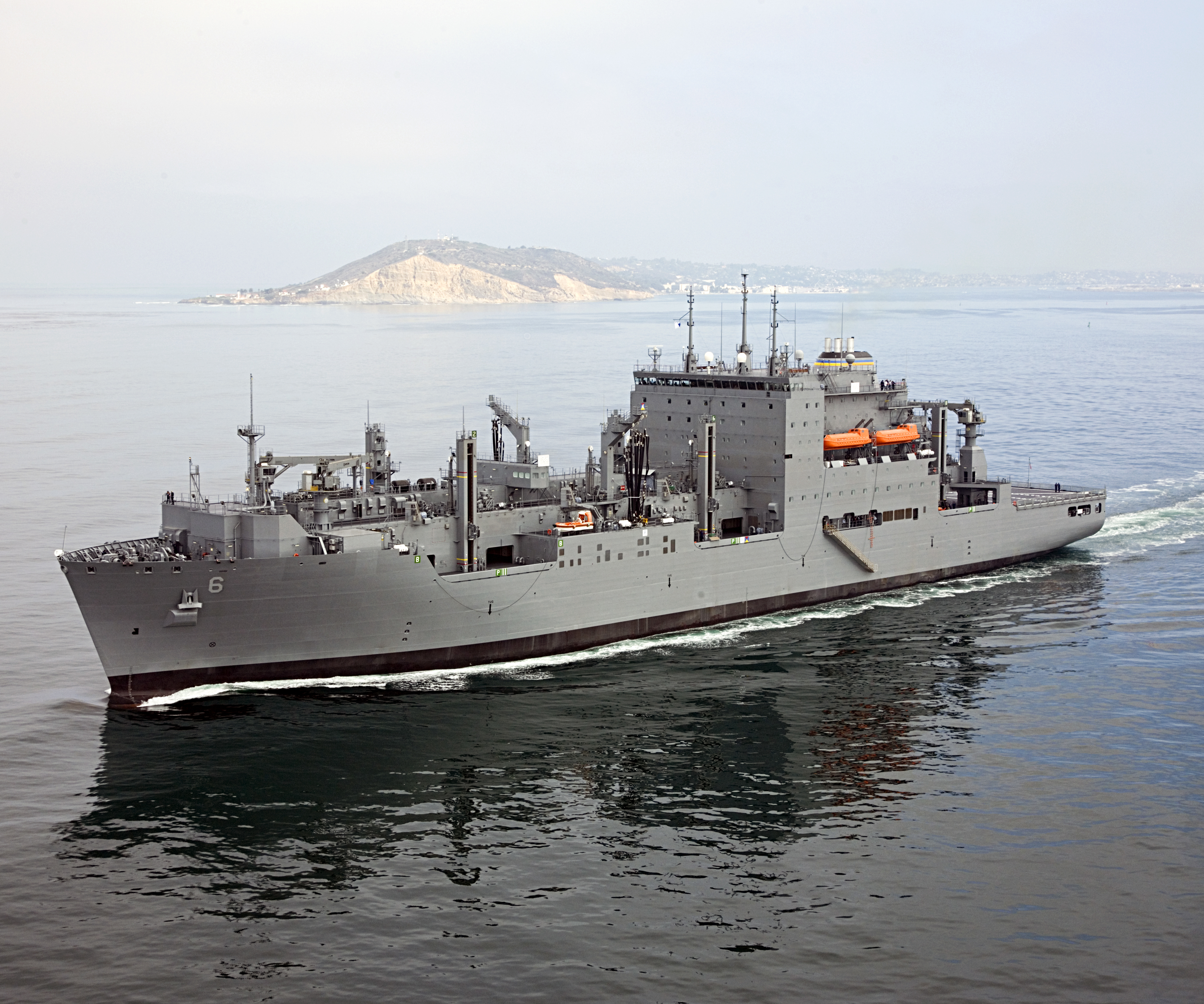 Dry Cargo/Ammunition Ship. Deliver supplies to customer ships at sea — ammunition, food, repair parts, stores and small quantities of fuel. Replace T-AE, T-AFS and T-AOE when operating with T-AO. Two dedicated ships provide ammunition, food, repair parts, stores and small quantities of fuel for the U.S. Marine Corps. Length: 689 ft, Beam: 106 ft, Displacement: 41,000 tons, Speed: 20 knots, Civilian: 129. Government-owned