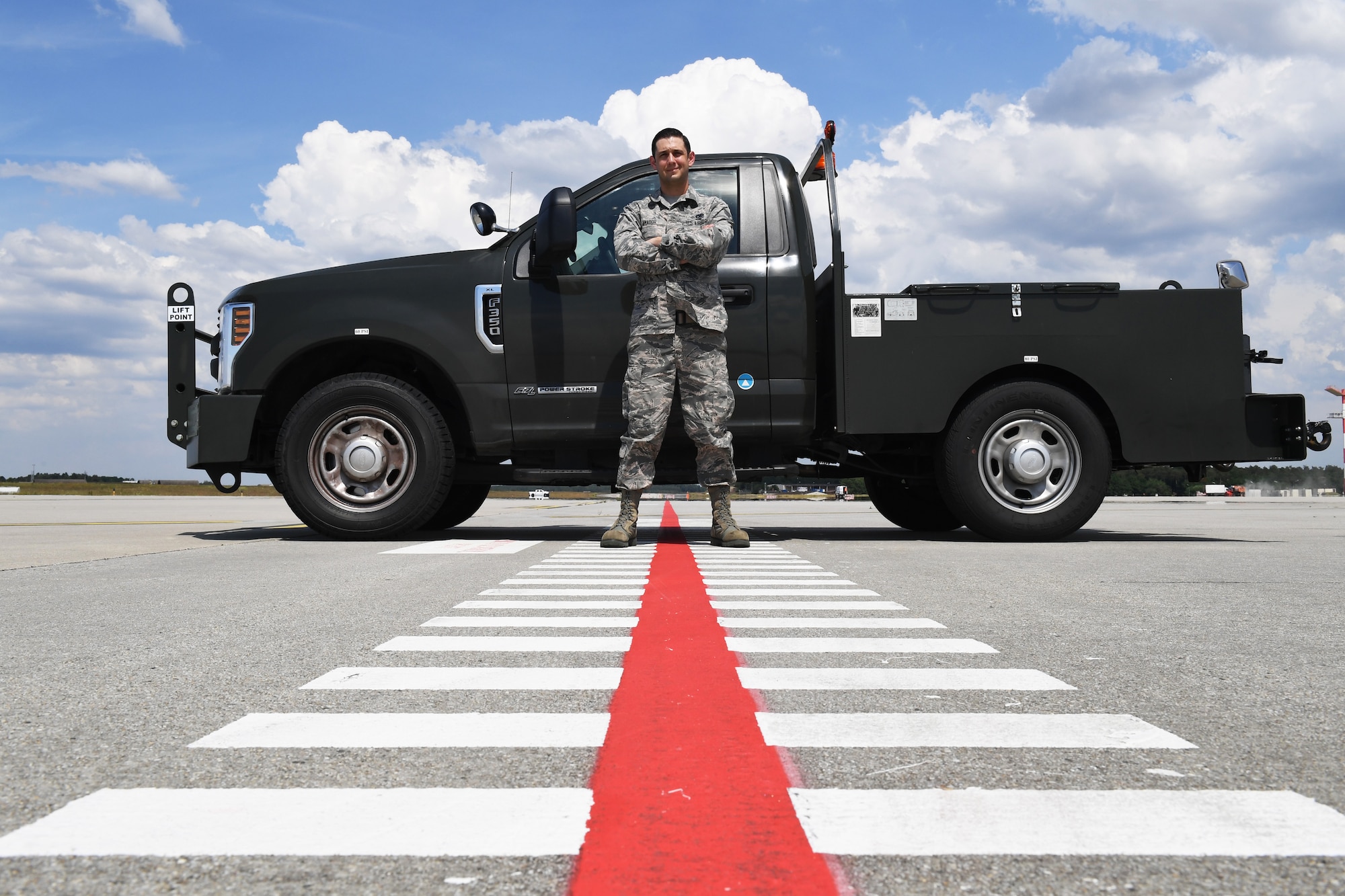 U.S. Air Force Senior Airman Ryan Amador, 52nd Maintenance Squadron Air Force repair enhancement program technician, poses for a photo on an entry control point on the flightline at Spangdahlem Air Base, Germany, June 3, 2020. Amador submitted an innovation idea that moved the ECP on Ramp 5 to a different location, allowing aerospace ground equipment drivers to reduce the amount of time spent towing assets on the flightline. (U.S. Air Force photo by Airman 1st Class Alison Stewart)