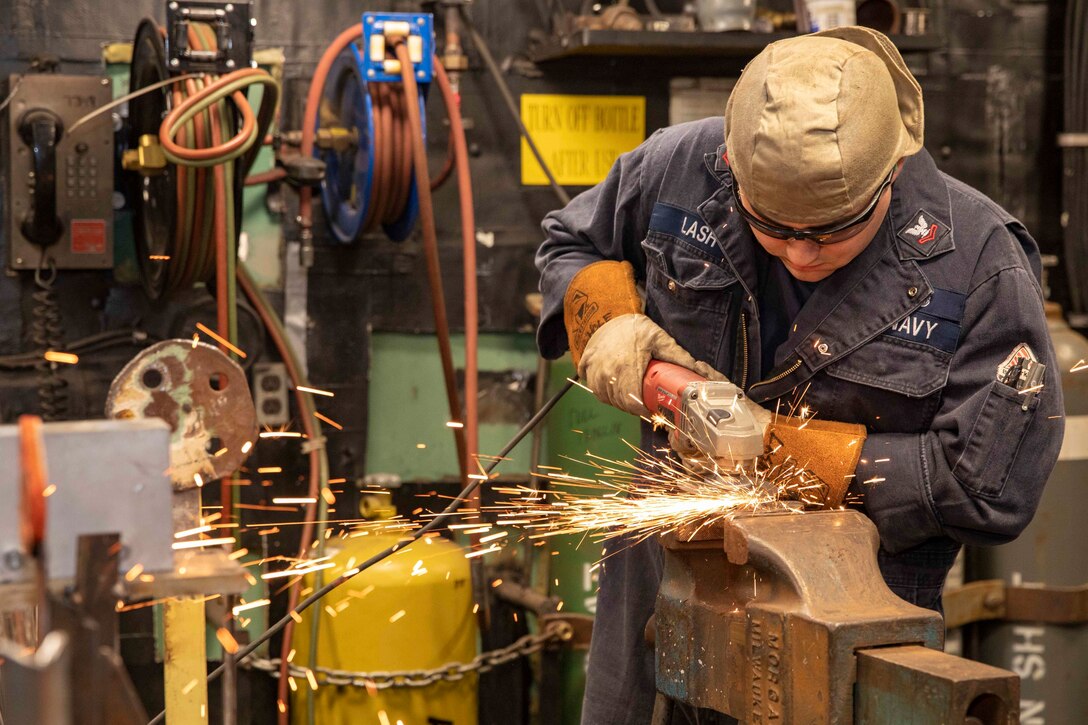 Sparks fly as a man grinds metal with a welding machine