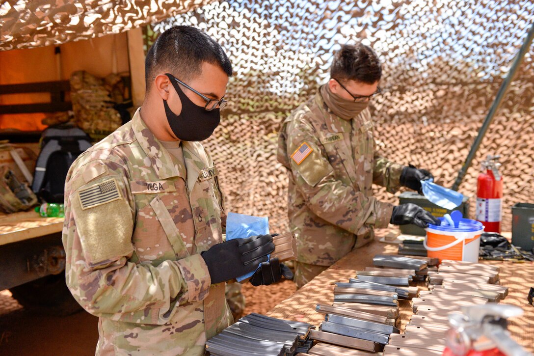 Two soldiers wipe down gun magazines.