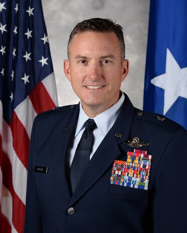 An U.S. Air Force general officer stands for an official photo in front of the American flag and general officer flag.