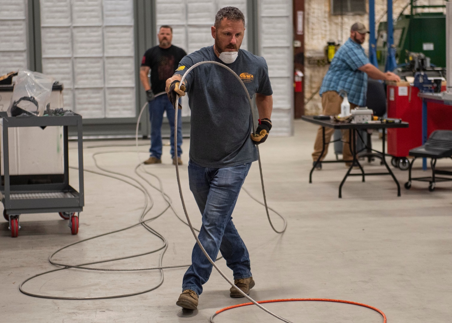 John Jacobs (front) and Cory Appling (back), mechanical and fiber optic technicians, prepare a Sensor Deployment Cable for installation on Carriage, Stream, Tow, and Recovery System (CSTRS) at the CSTRS Depot May 5.