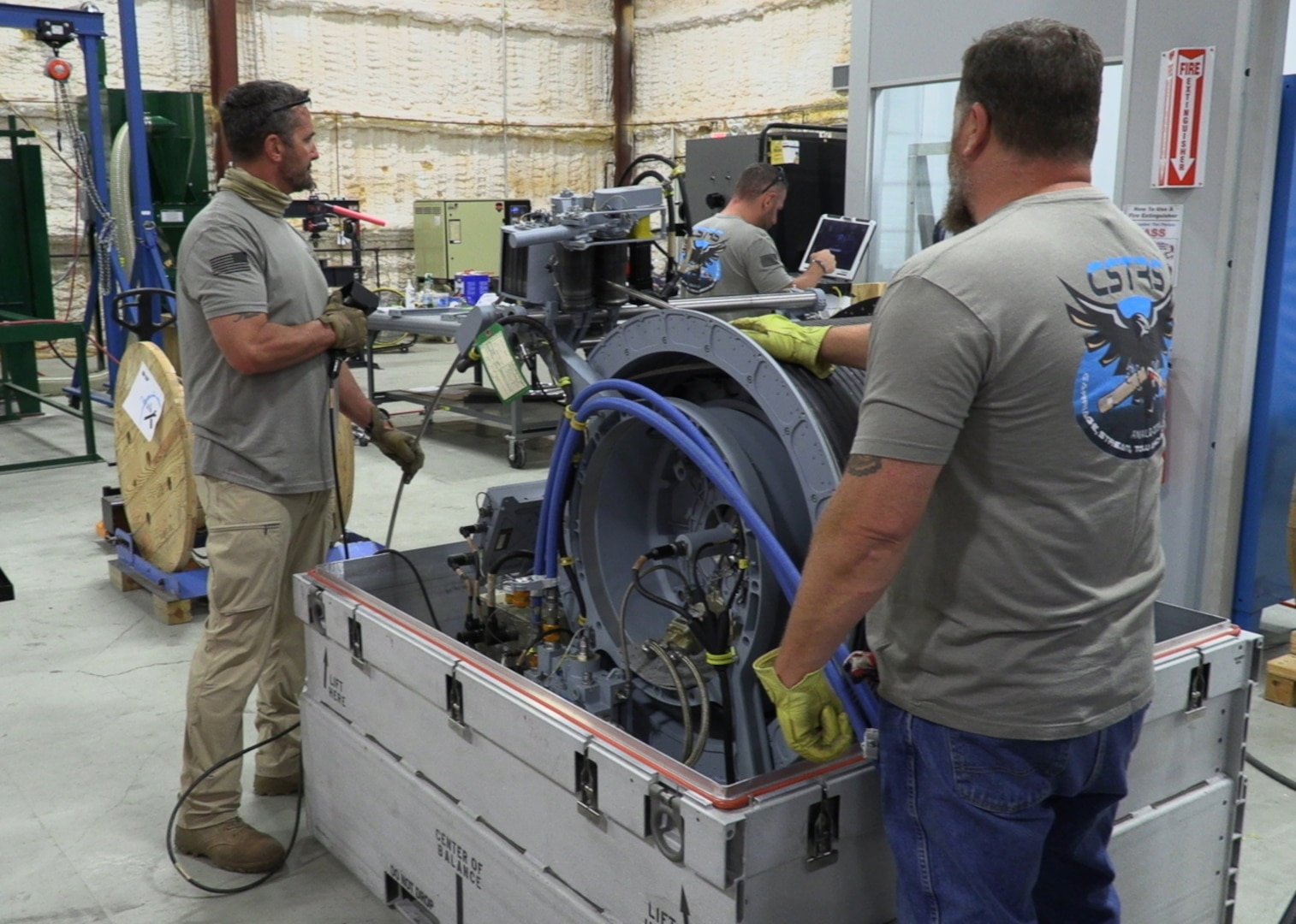 Derek Decker, mechanical technician and fleet support team lead assists with SD Cable installation on the hydraulic winch of a Carriage, Stream, Tow, and Recovery System (CSTRS) at the CSTRS Depot May 5.