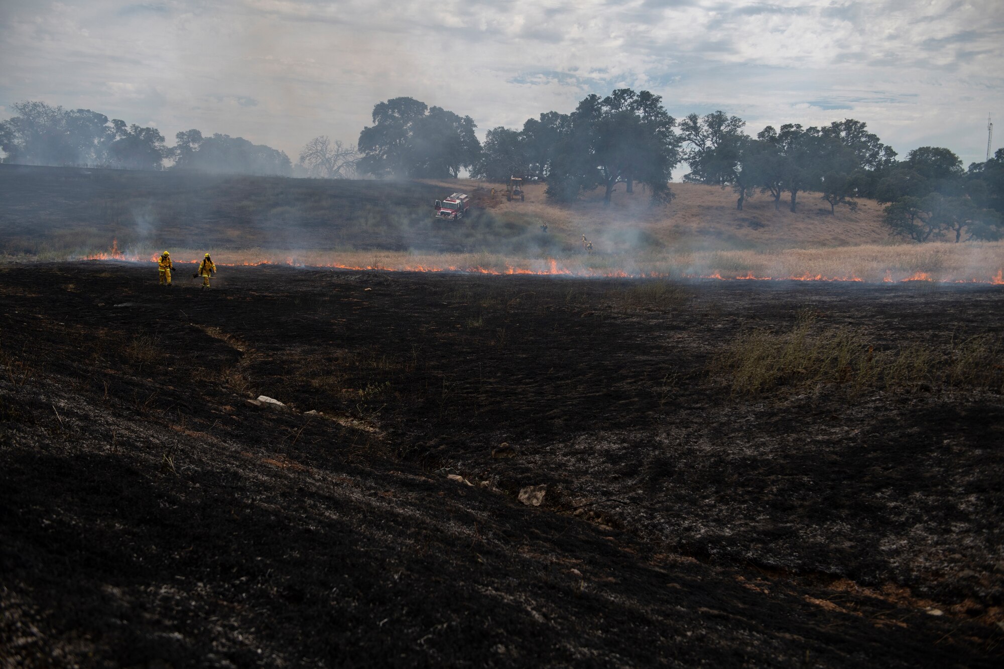 9th Civil Engineer Squadron firefighters walk through a wildfire on Beale Air Force Base.