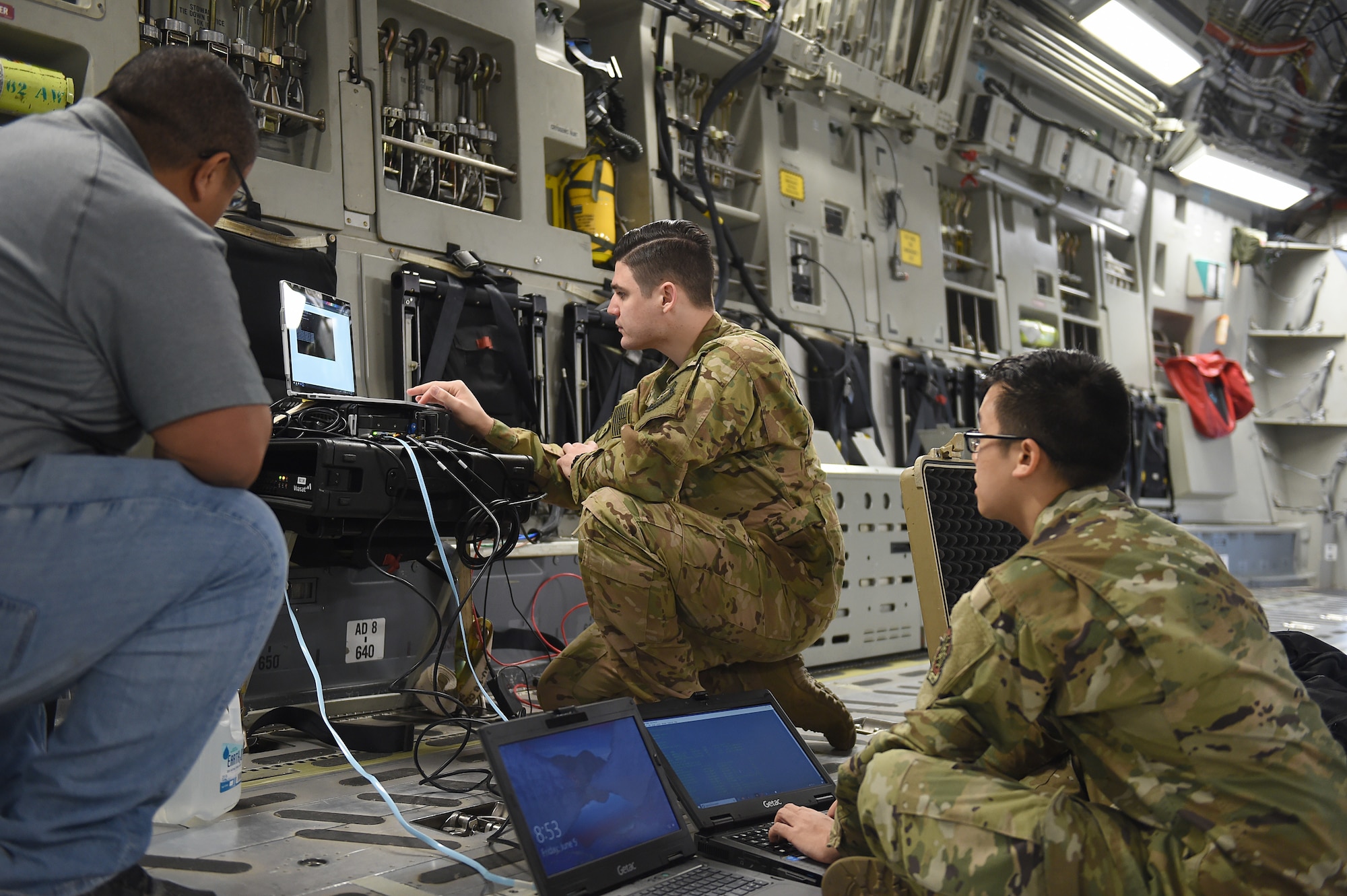 From left to right, Joseph Labosa, Department of Defense contractor, Staff Sgt. Mehmet Yasdiman, 1st Airlift Squadron communications systems operator, and Staff Sgt. Richie Sounantha, Air Mobility Command cyber transport systems technician, test a fixed installation satellite antenna (FISA) connection onboard a C-17 Globemaster III on Joint Base Lewis-McChord, Wash., June 5, 2020. The FISA was set up to work with a dynamic re-tasking capability (DRC) system, enabling higher connection speeds and more efficient communication between the aircraft and the ground. (U.S. Air Force photo by Airman 1st Class Mikayla Heineck)