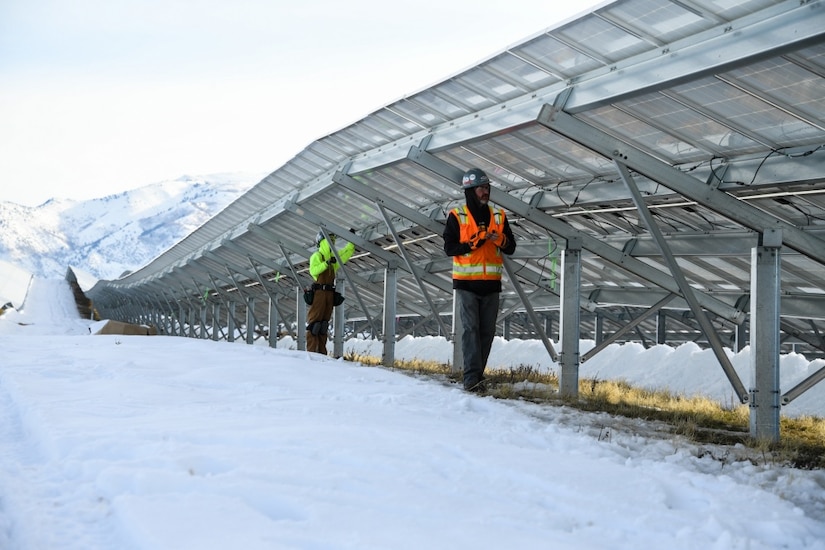 Two airmen work on solar panels.