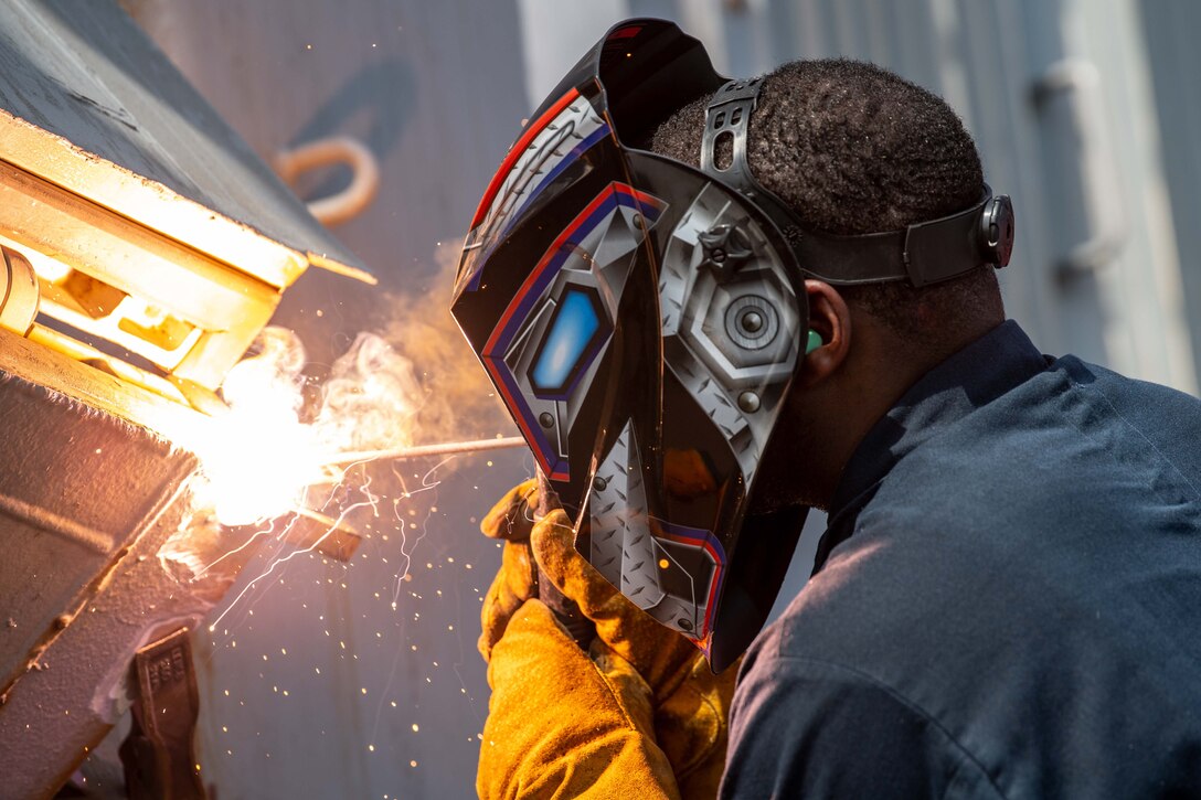 A man uses a torch to weld a metal door.