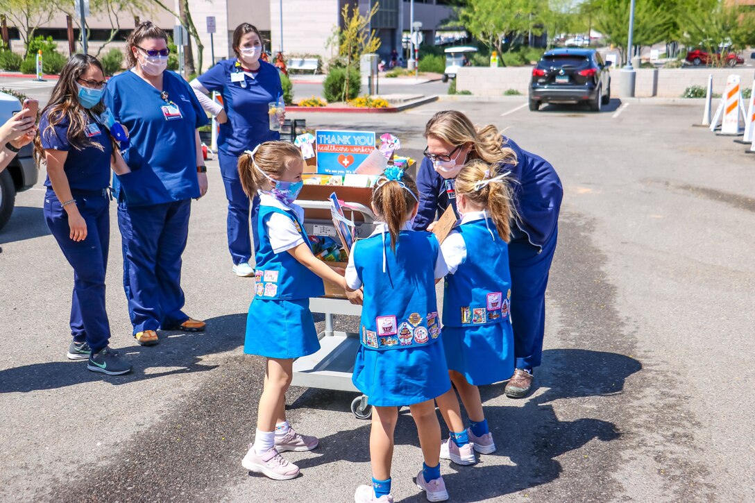 Nurses receive a package of treats from children in front of a hospital