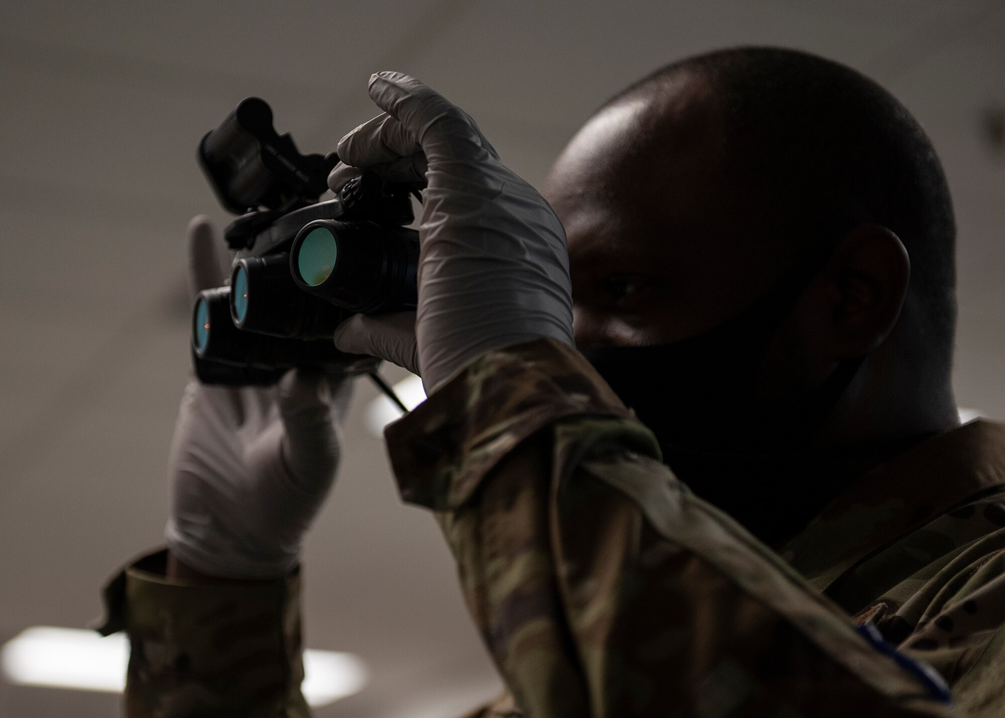 An airman looks through a pair of night vision goggles.