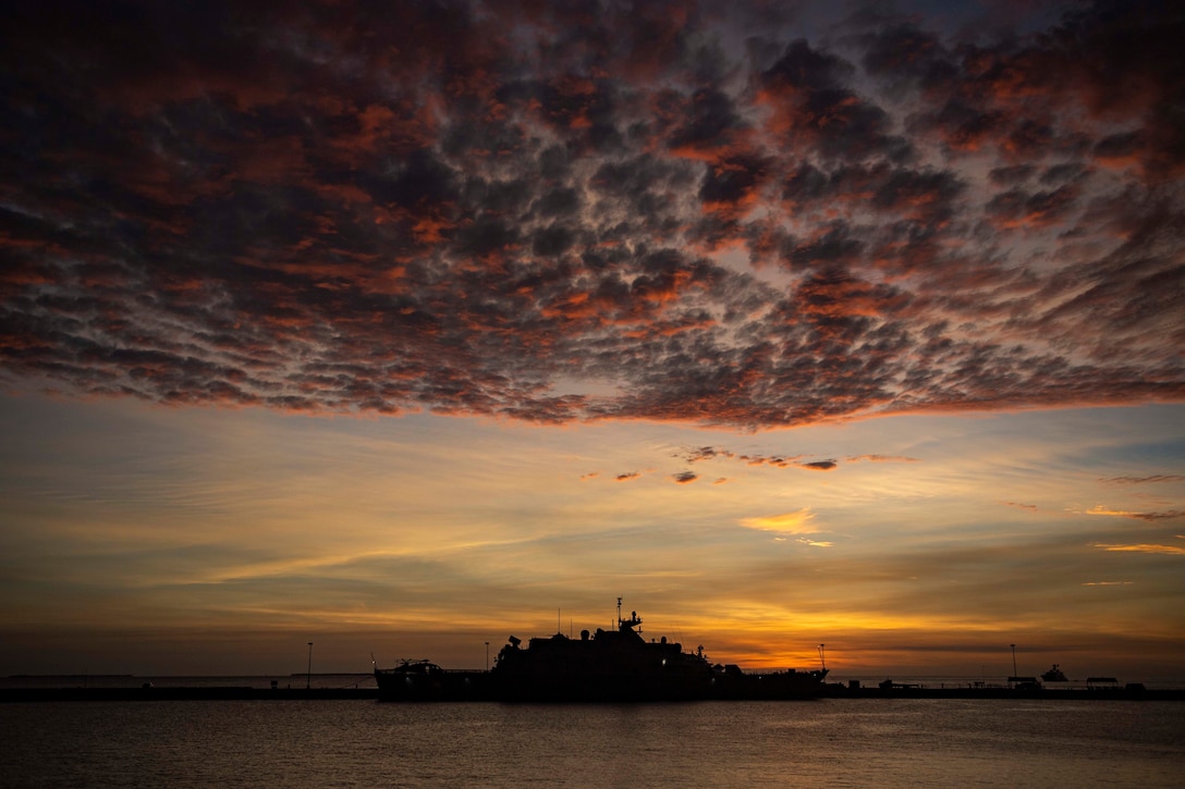 A military ship sits in port at twilight.