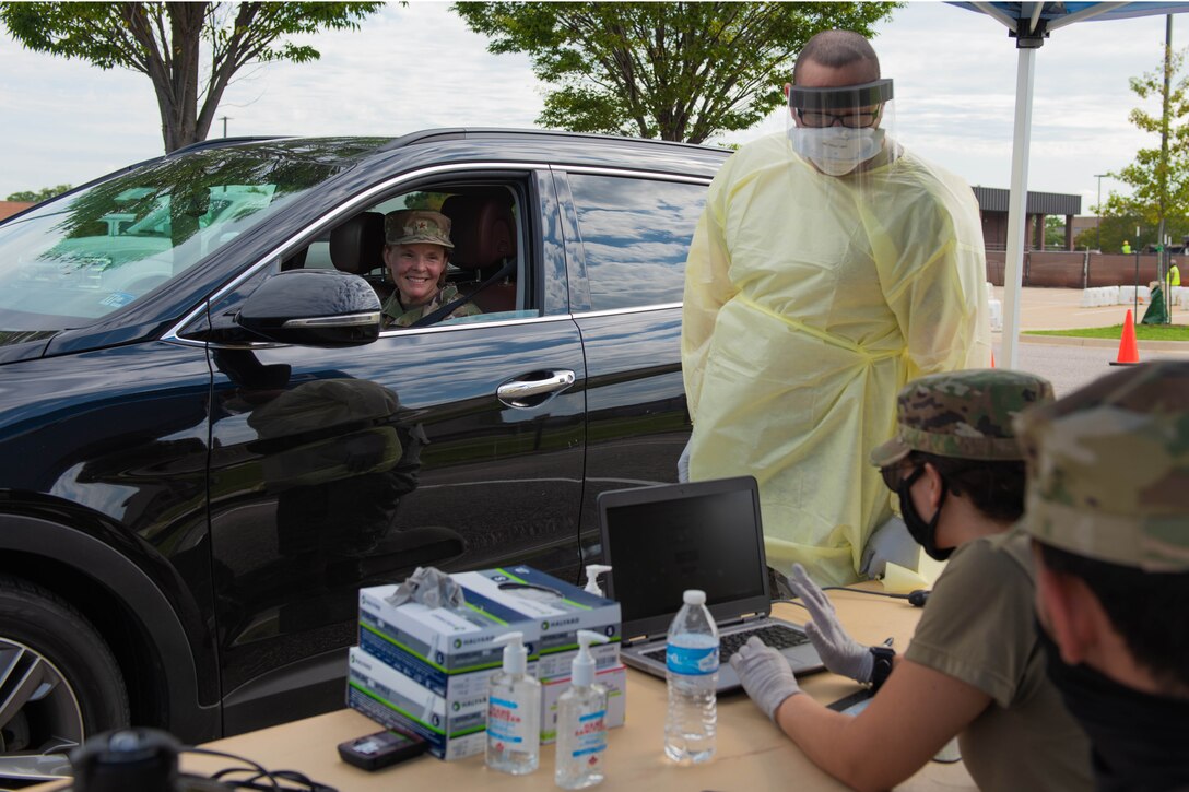 A woman driving a car stops at a COVID-19 testing station.