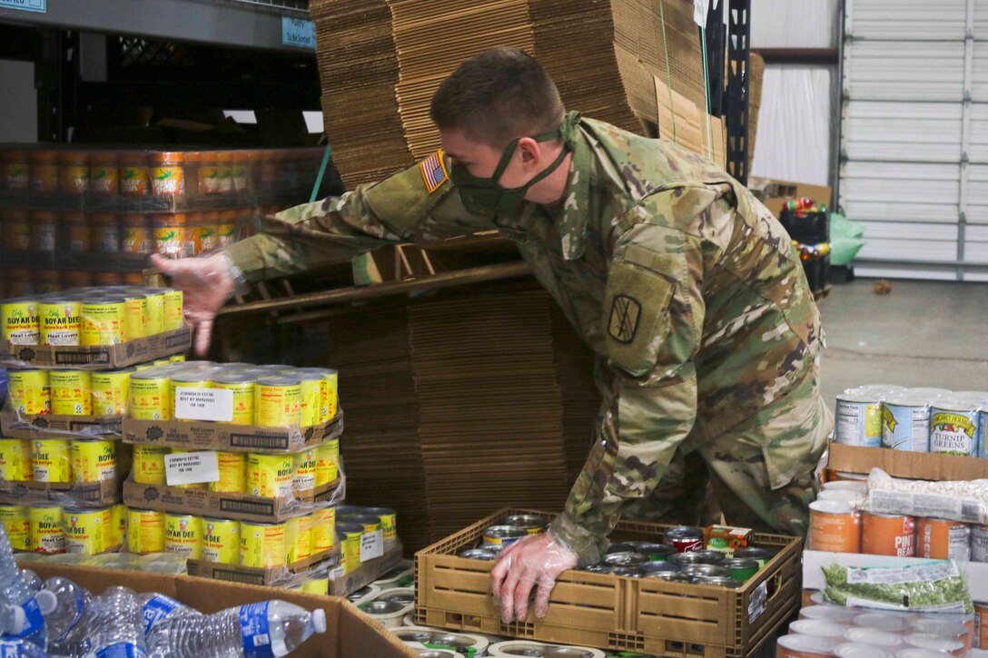 A soldier sorts packages of cans.