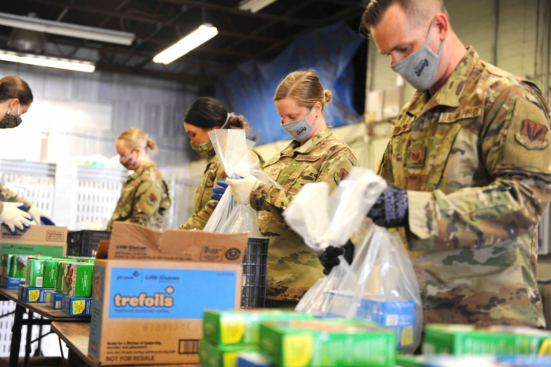 Ohio National Guardsmen put packages of food into plastic bags.