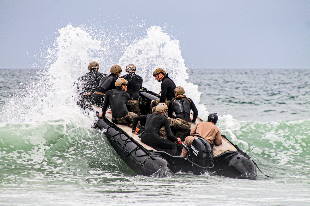 Sailors in an inflatable boat create a splash while maneuvering over a wave.