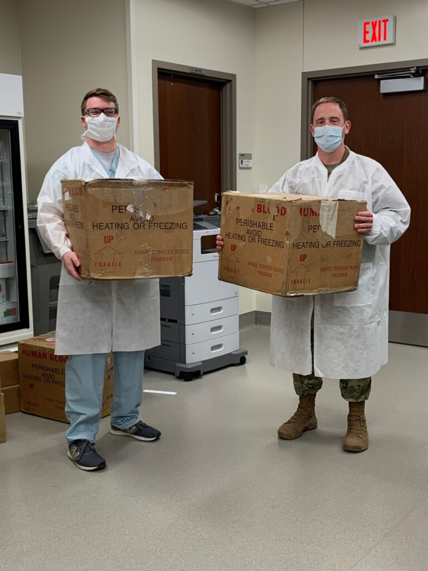 Lab assistants from Wilford Hall Medical Center at Lackland Air Force Base, Texas, hold up packages containing nasal swabs that are to be delivered to Brooke Army Medical Center to test for COVID-19, May 20, 2020. The swabs were collected, delivered, and tested in a 12-hour span. (Courtesy Photo)