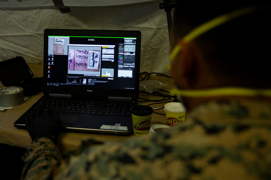 U.S. Marine Corps Cpl. Andrew Castillo, a military police officer with Battalion Landing Team 1/4, 15th Marine Expeditionary Unit, examines fingerprints recovered from a tactical site exploitation during a raid exercise for realistic urban training at Marine Corps Base Camp Pendleton, California, June 6, 2020. Marines use fingerprinting to gather evidence from tactically exploited sites to aid in the prosecution of criminals. (U.S. Marine Corps photo by Cpl. Patrick Crosley)