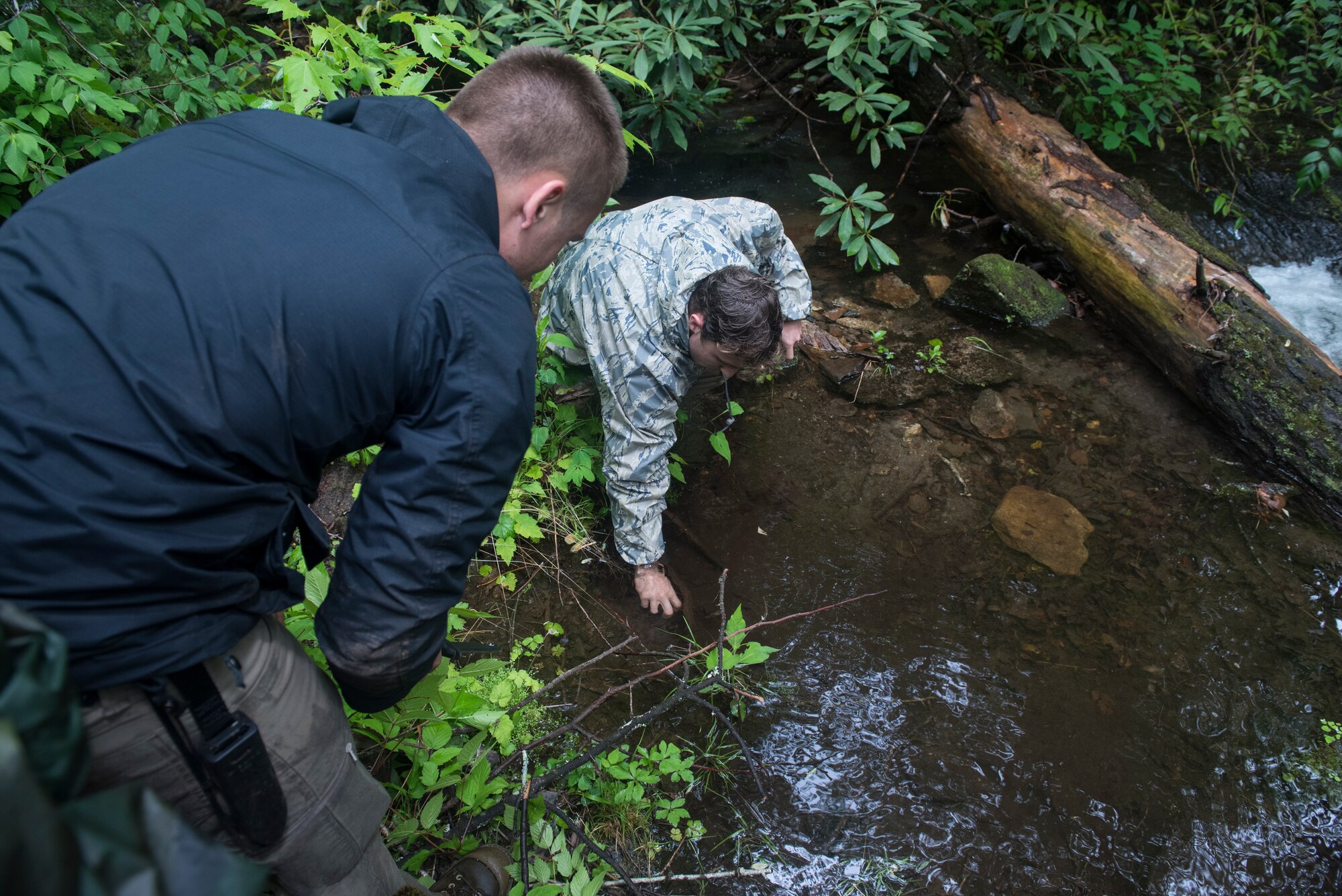 Senior Airman Adrian Montgomery, 4th Component Maintenance Squadron aerospace propulsion journeyman, left, and Senior Airman Greg Sherman, 334th Aircraft Maintenance Unit load crew team chief, gather water near Brevard, North Carolina, May 21, 2020. For three days, Montgomery, Sherman and three others lived off the land drinking water they purified and eating plants they could find during combat survival training. (U.S. Air Force photo by Senior Airman Kenneth Boyton)