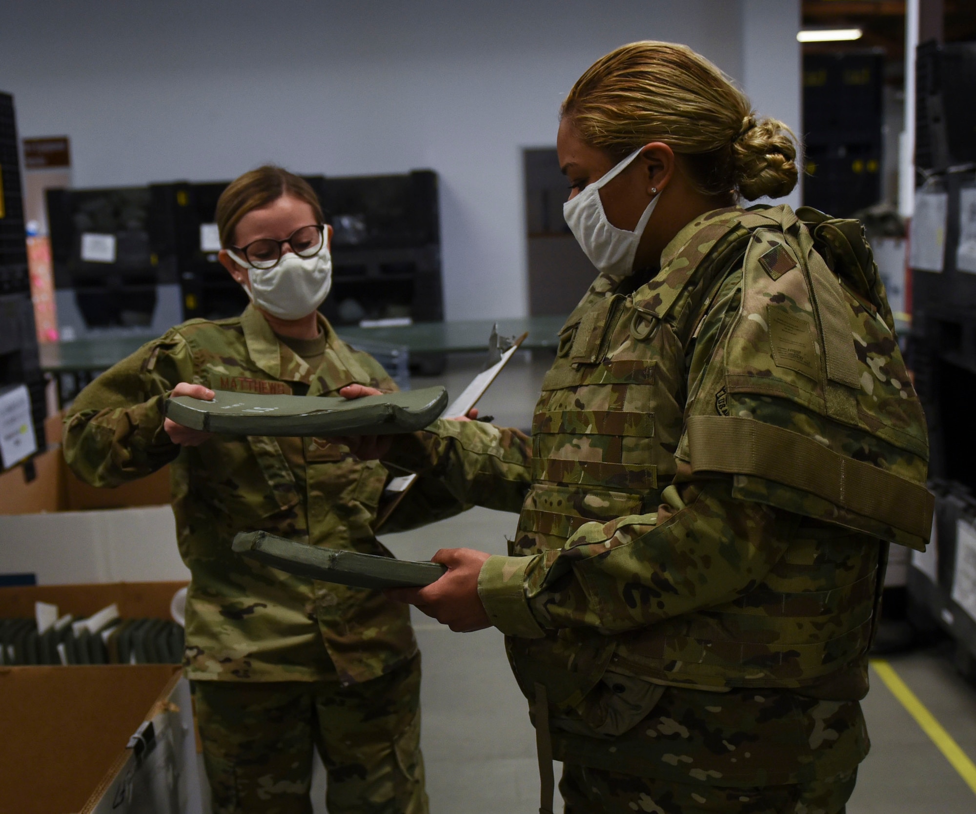 U.S. Air Force Airman 1st Class Bruna Matthews, left, 52nd Logistics Readiness Squadron Individual Protective Equipment apprentice, and Senior Airman Alyssa Padilla, right, 52nd LRS IPE journeyman, demonstrate prepping a vest, June 4, 2020, at Spangdahlem Air Base, Germany. LRS Airmen learned to adjust to the rapid changes of the COVID-19 pandemic, and executed their mission of ensuring the 52nd Fighter Wing and surrounding geographically separated units were properly equipped with protective gear during this pandemic. (U.S. Air Force photo by Senior Airman Melody W. Howley)