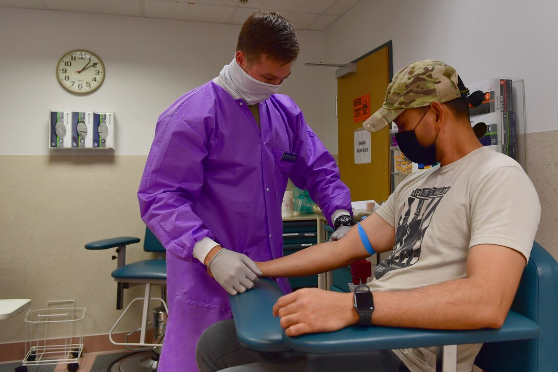 An Airman prepares a man's arm to take blood.