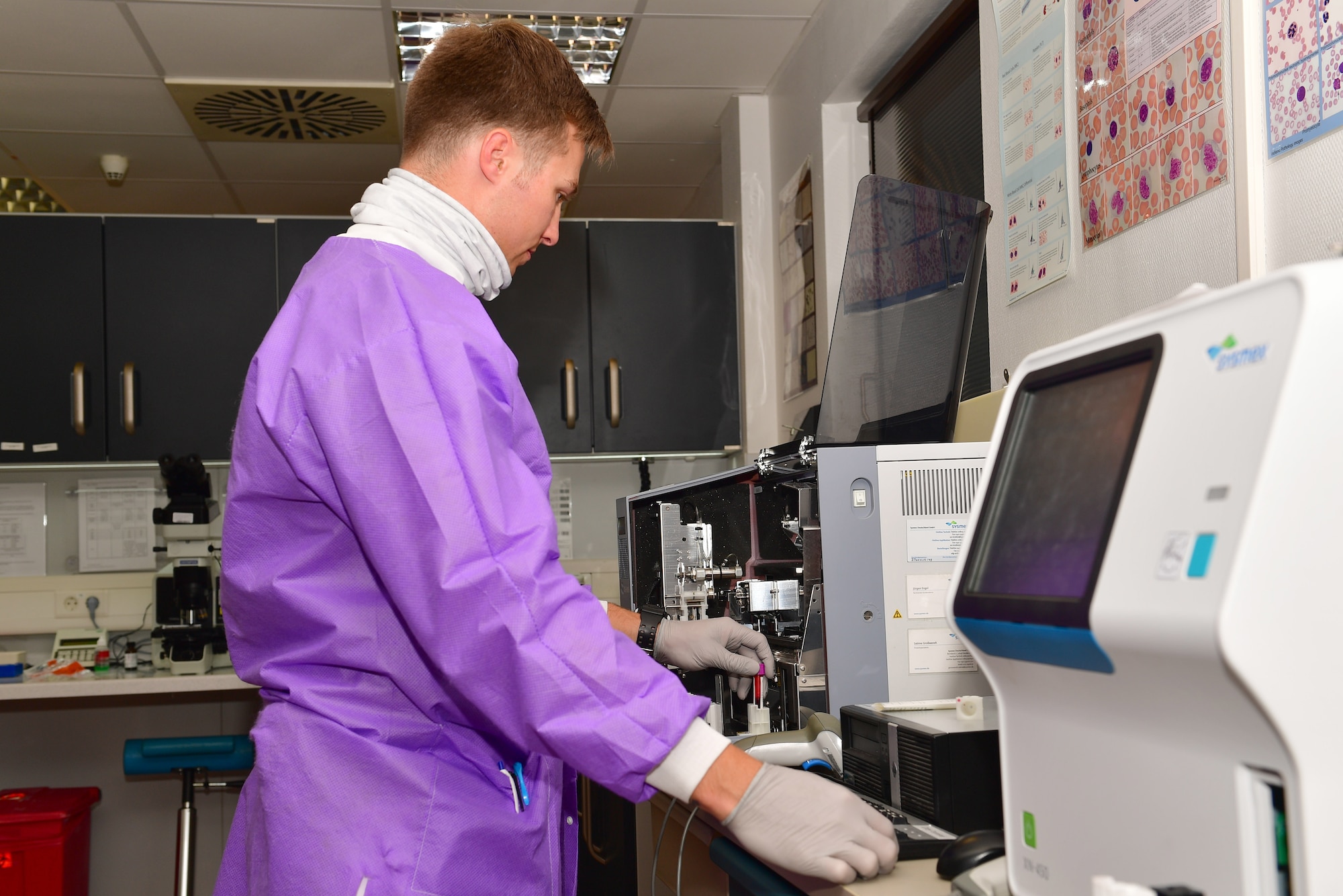 An Airman places a blood sample in a machine for analysis.