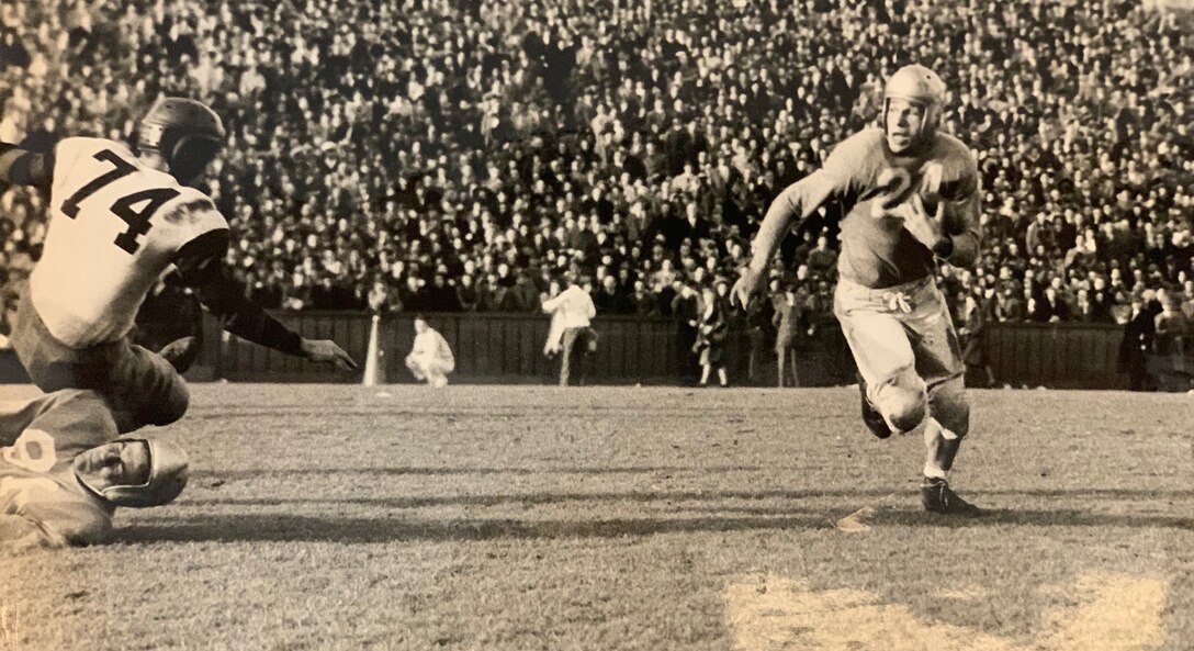 A football player carrying the ball attempts and end run around an advancing defensive lineman.