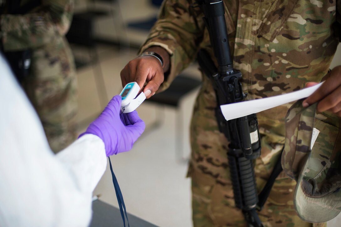 A soldier receives a COVID-19 test from a person wearing personal protective equipment.