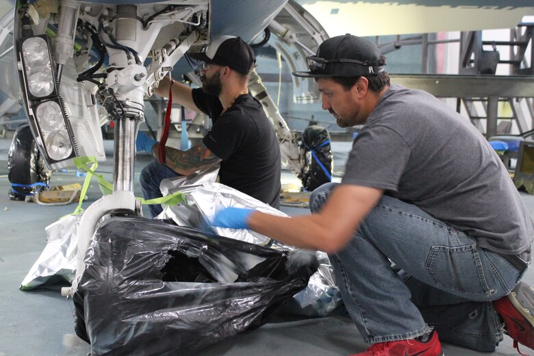 576th Aircraft Maintenance Squadron paint shop technicians, Ben Gifford (left) and Jayson Chavez remove protective coverings from an F-16 Fighting Falcon they helped paint with a “ghost” paint scheme at Hill Air Force Base, Utah, May 21, 2020. The paint scheme is intended to replicate an adversary’s fighter jet. United States, allied, and partner-nation aircrews routinely train against accurate and realistic threats including aircraft painted to replicate those pilots might see in aerial combat. (U.S. Air Force photo by Donovan Potter)