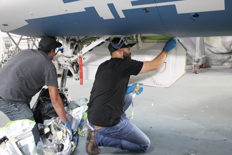576th Aircraft Maintenance Squadron paint shop technicians, Jayson Chavez (left) and Ben Gifford remove protective coverings from an F-16 Fighting Falcon they helped paint with a “ghost” paint scheme at Hill Air Force Base, Utah, May 21, 2020. The paint scheme is intended to replicate an adversary’s fighter jet. United States, allied, and partner-nation aircrews routinely train against accurate and realistic threats including aircraft painted to replicate those pilots might see in aerial combat. (U.S. Air Force photo by Donovan Potter)