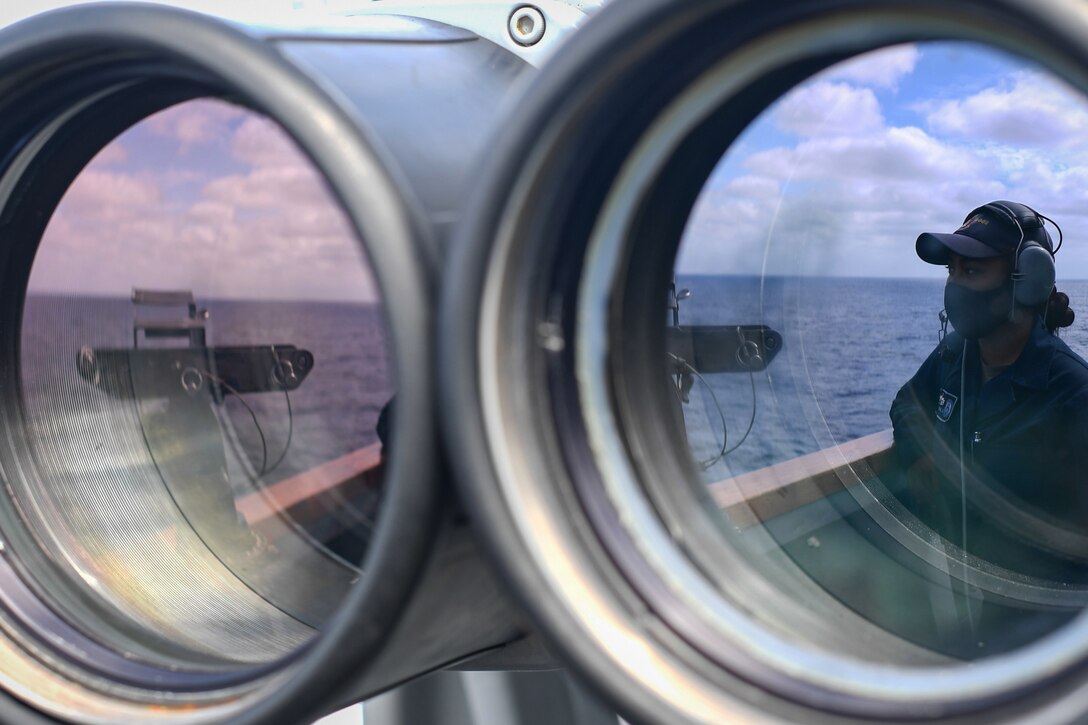 A sailor is seen through binocular lenses.