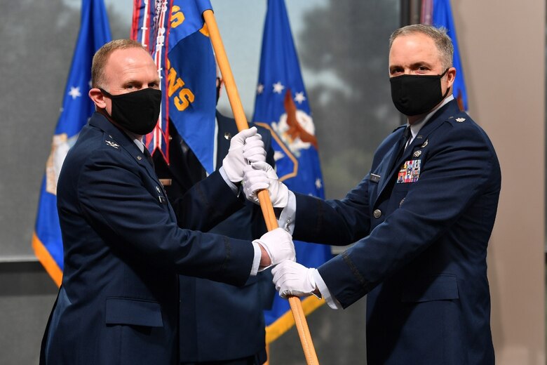 Col. Brian Kehl, 50th Mission Support Group commander, passes the 50th Contracting Squadron guidon to Lt. Col. Gerald Allen, incoming 50th CONS commander, during a change of command ceremony at Schriever Air Force Base, Colorado, June 10, 2020. Allen is the incoming commander of 50th CONS after serving as the deputy for the Contracting Force Development Division, Office of the Secretary of the Air Force (Contracting), the Pentagon, Washington, D.C. (U.S. Air Force photo by Dennis Rogers)